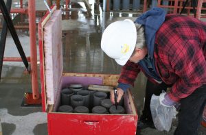 Technician marking concrete samples for field curing