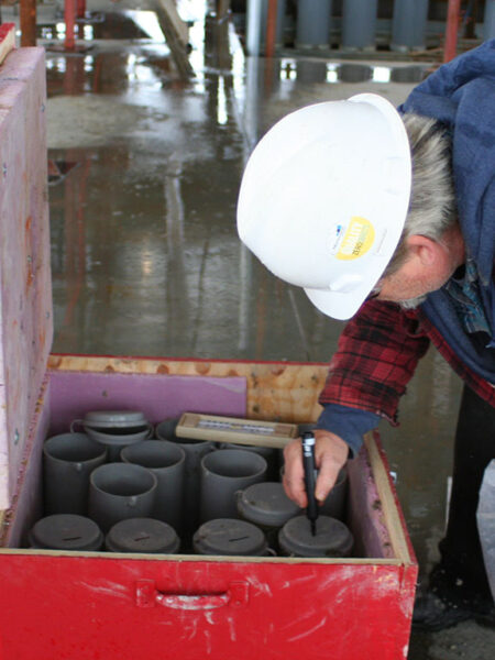 Technician marking concrete samples for field curing